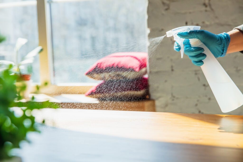 Main dans des gants désinfectant les surfaces avec désinfectant à la maison