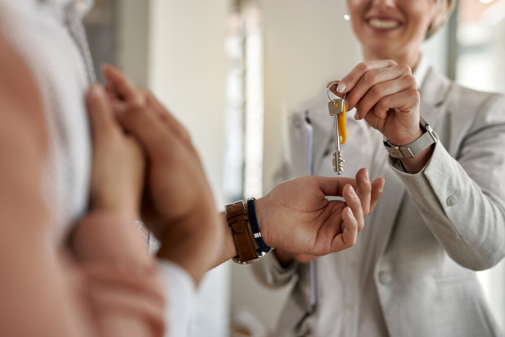 Gros plan d’un couple recevant les clés de leur nouvel appartement de l’agent immobilier