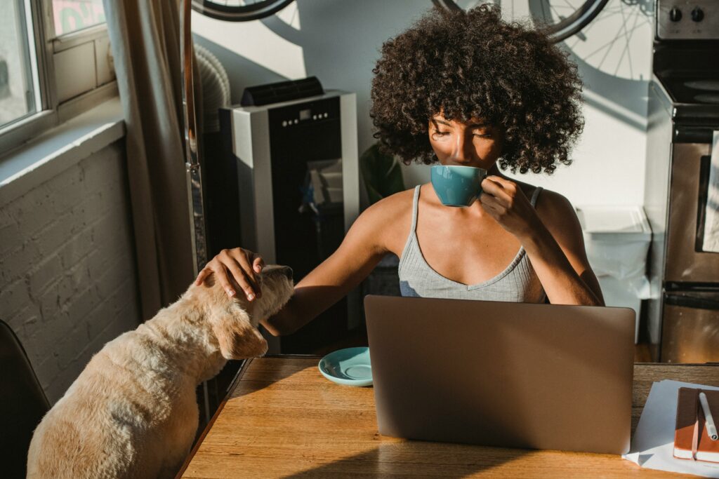 Femme afro-américaine freelancer utilisant un ordinateur portable et buvant du café