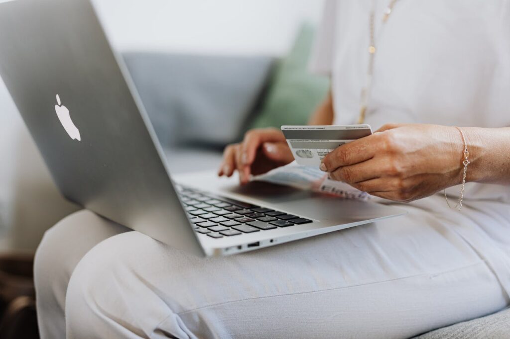 Personne utilisant un MacBook et tenant une carte de crédit
