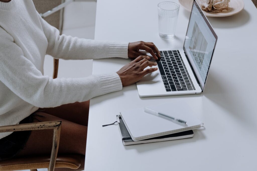 Personne en chemise blanche à manches longues utilisant Macbook Pro