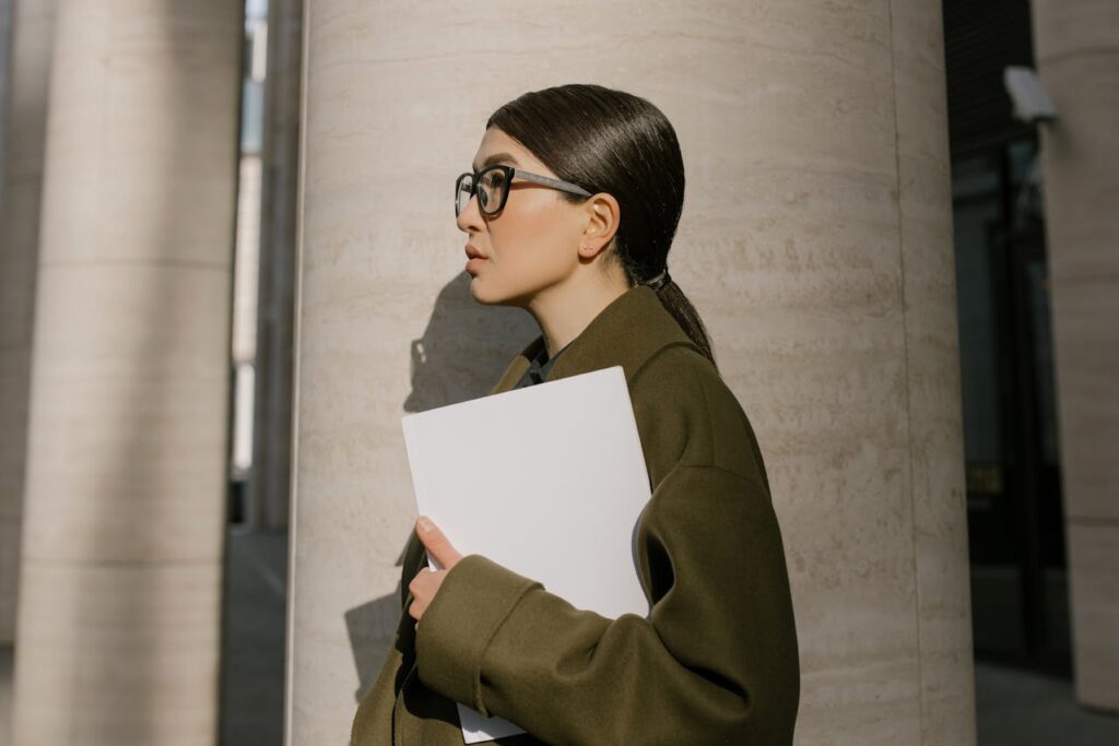 Femme en manteau vert debout à côté de la colonne de béton