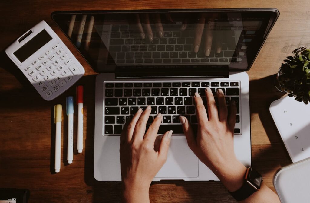 Personne utilisant Macbook Pro sur une table en bois marron